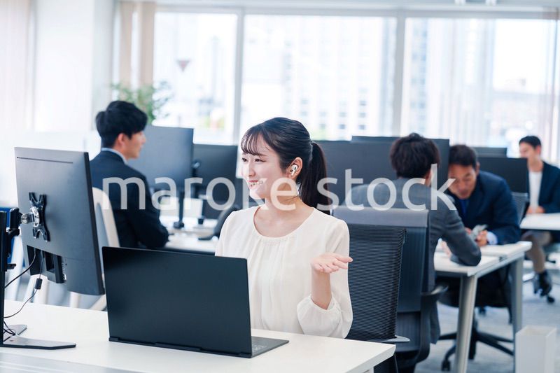 ワイヤレスイヤホンを使いオフィスでリモート会議をする女性