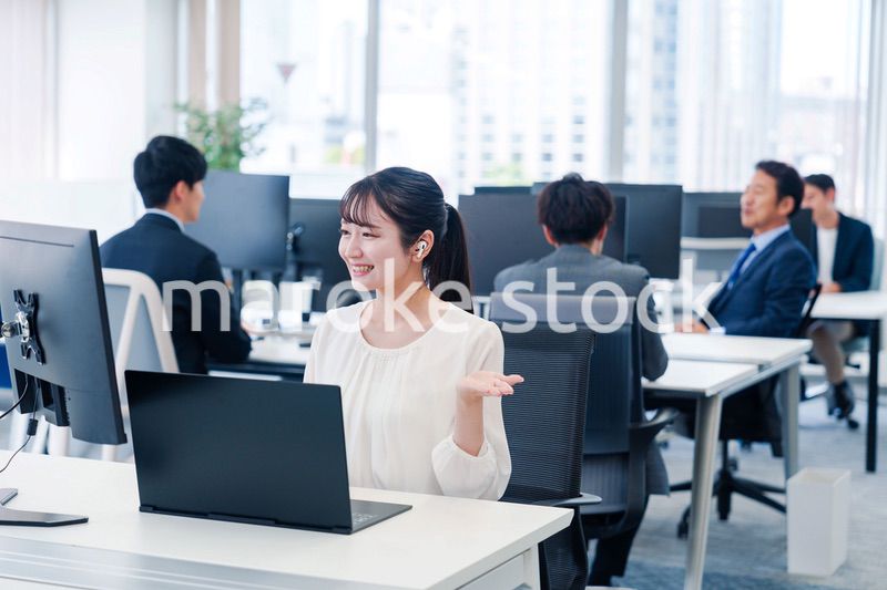 ワイヤレスイヤホンを使いオフィスでリモート会議をする女性