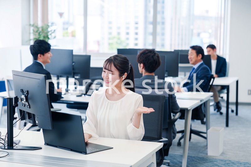 ワイヤレスイヤホンを使いオフィスでリモート会議をする女性