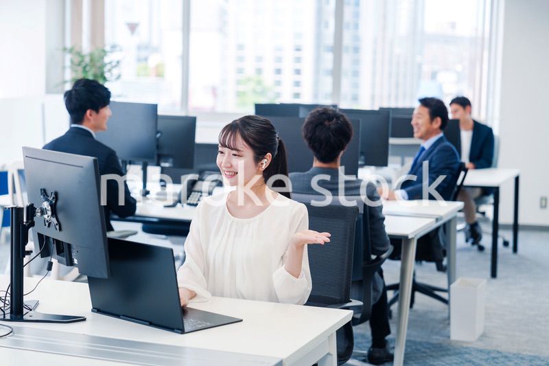 ワイヤレスイヤホンを使いオフィスでリモート会議をする女性