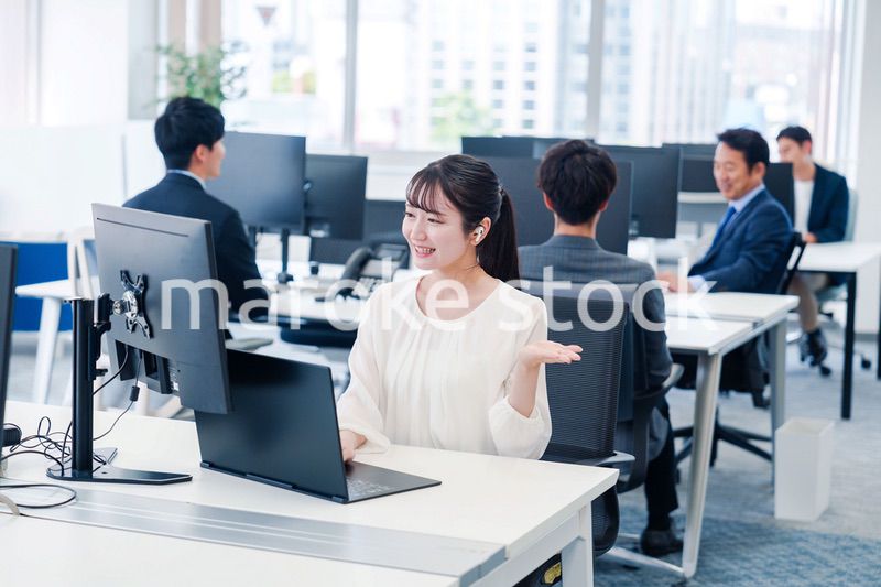 ワイヤレスイヤホンを使いオフィスでリモート会議をする女性