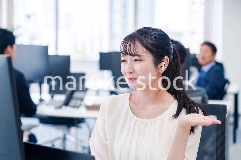 ワイヤレスイヤホンを使いオフィスでリモート会議をする女性