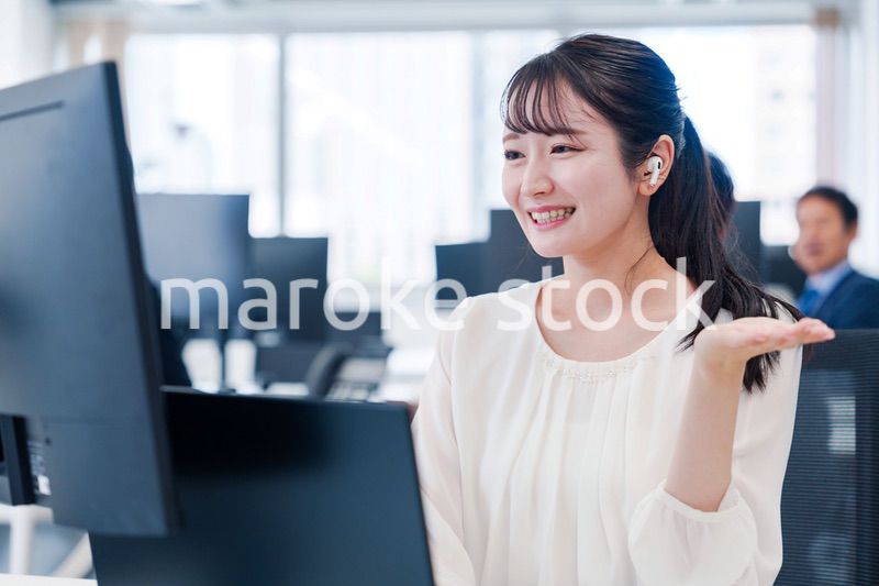 ワイヤレスイヤホンを使いオフィスでリモート会議をする女性