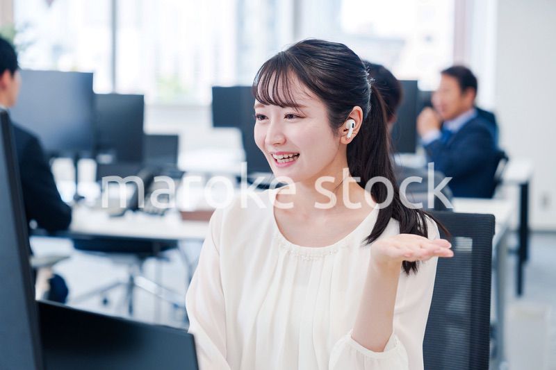 ワイヤレスイヤホンを使いオフィスでリモート会議をする女性