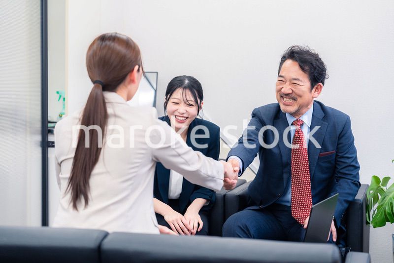 笑顔で握手を交わす3人のビジネスパーソン