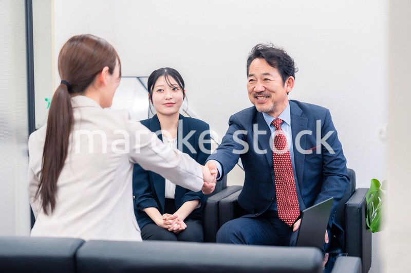 笑顔で握手を交わす3人のビジネスパーソン