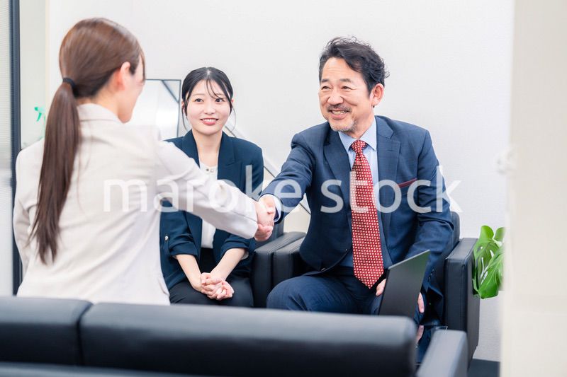 笑顔で握手を交わす3人のビジネスパーソン