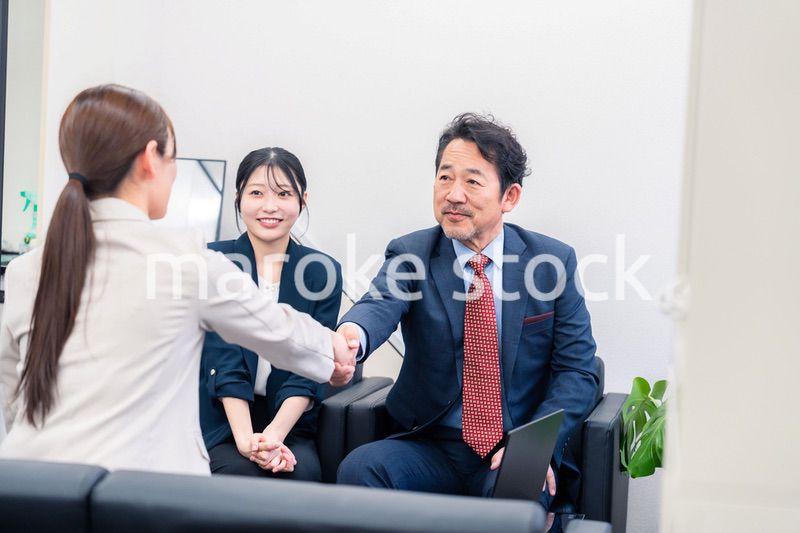 笑顔で握手を交わす3人のビジネスパーソン