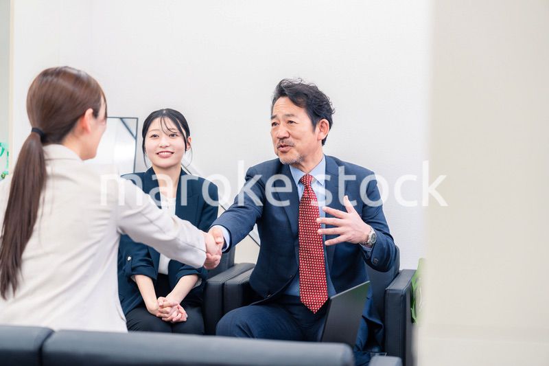 笑顔で握手を交わす3人のビジネスパーソン