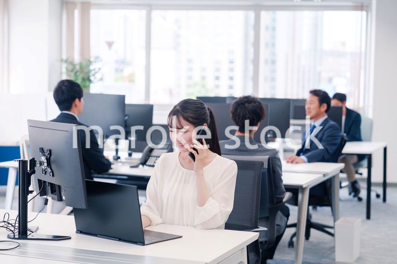 オフィスの中でスマホで通話をするビジネスパーソン