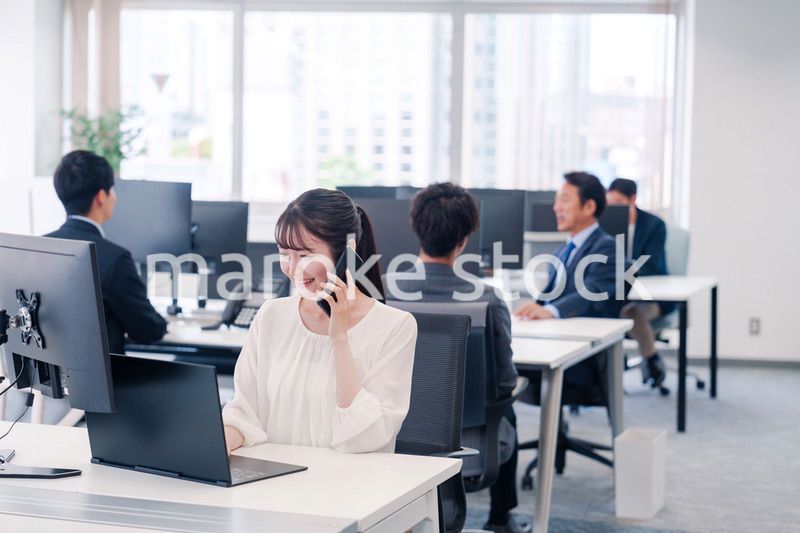 オフィスの中でスマホで通話をするビジネスパーソン