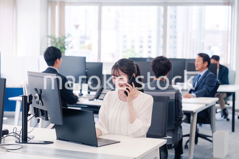 オフィスの中でスマホで通話をするビジネスパーソン