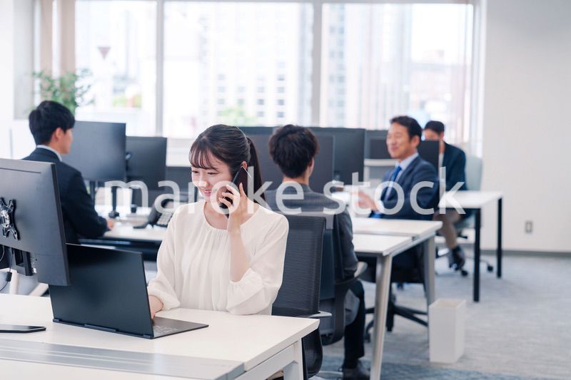 オフィスの中でスマホで通話をするビジネスパーソン