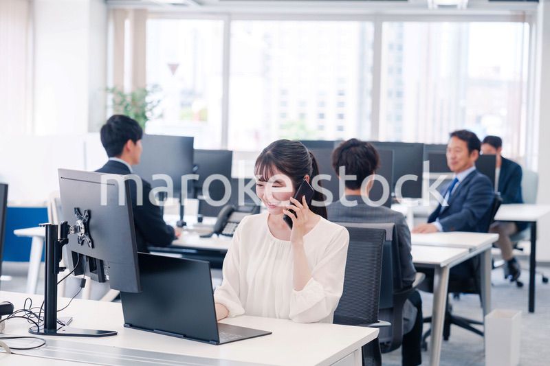 オフィスの中でスマホで通話をするビジネスパーソン