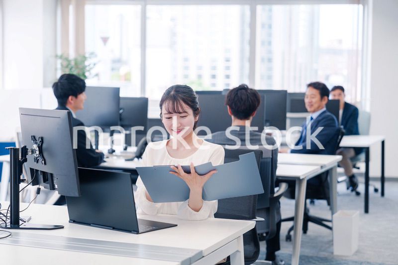 オフィスで笑顔でデスクワークをする若い女性