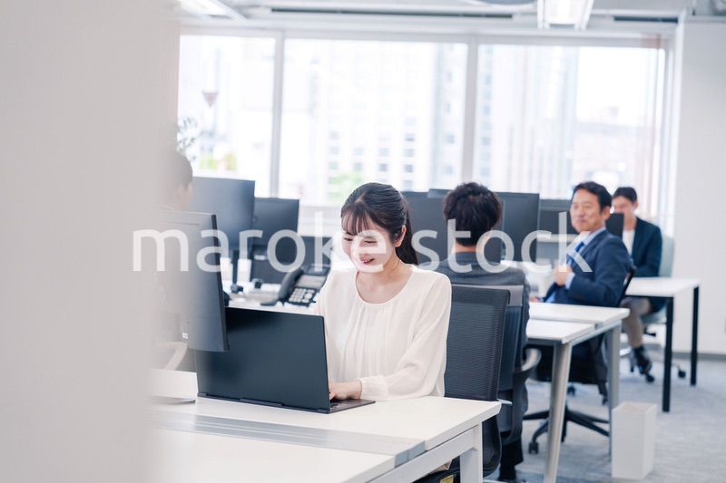 オフィスで笑顔でデスクワークをする若い女性