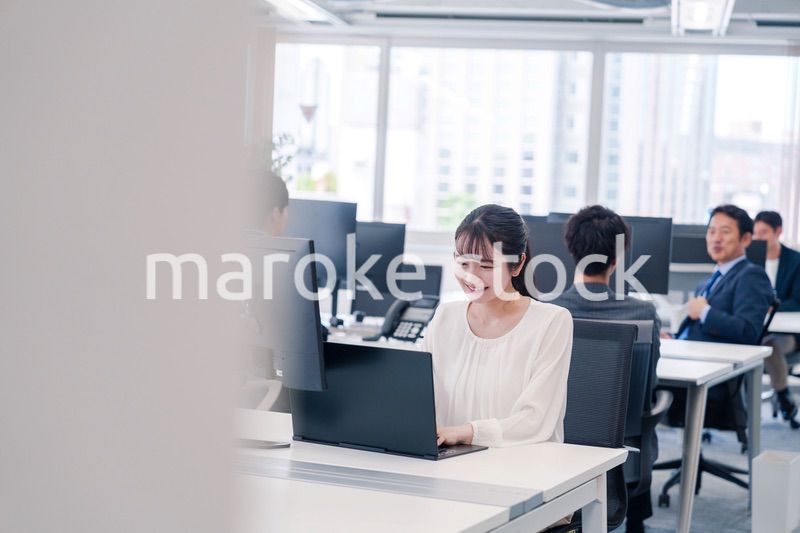 オフィスで笑顔でデスクワークをする若い女性