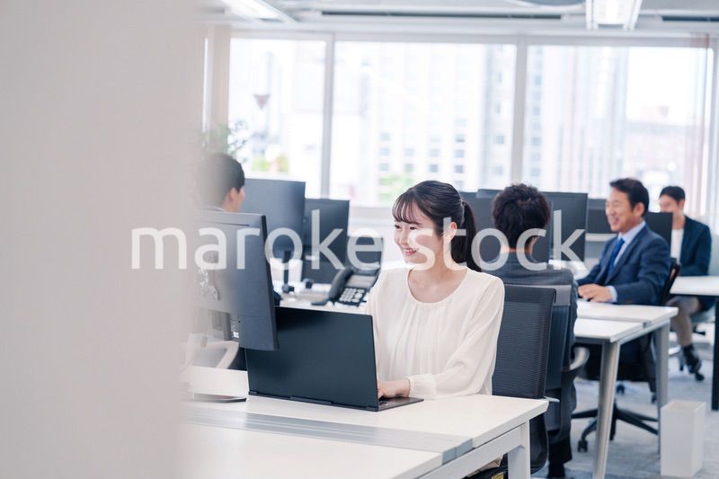 オフィスで笑顔でデスクワークをする若い女性