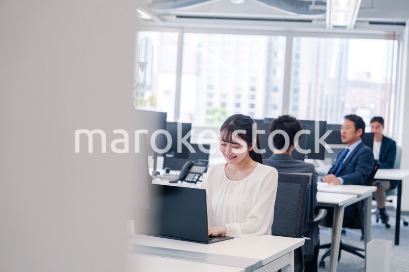 オフィスで笑顔でデスクワークをする若い女性