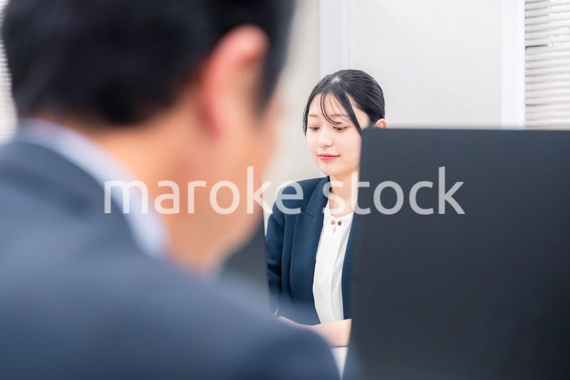 オフィスで生き生きとデスクワークをする若い女性