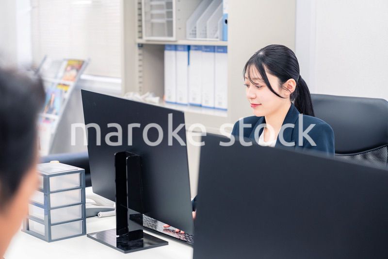 オフィスで生き生きとデスクワークをする若い女性