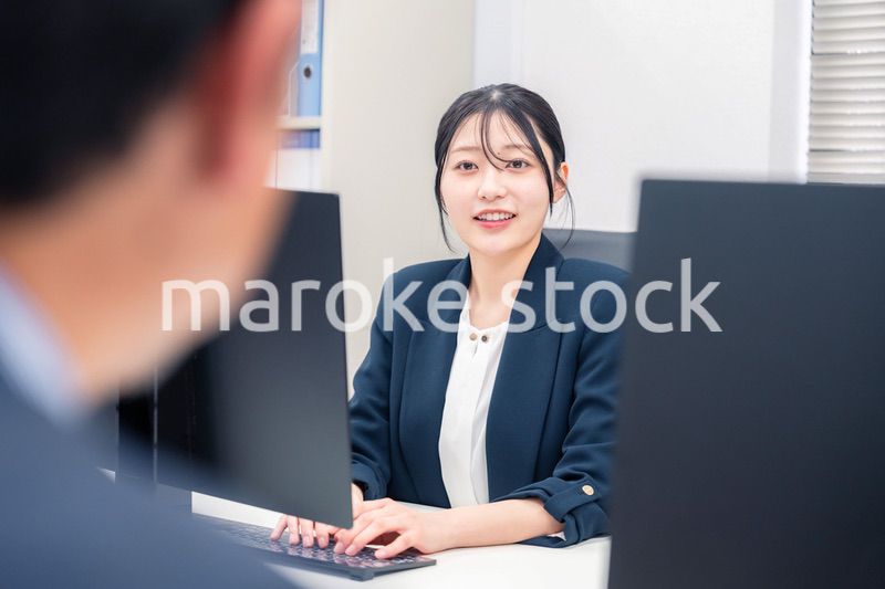 オフィスで生き生きとデスクワークをする若い女性