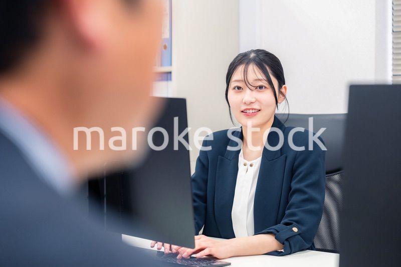 オフィスで生き生きとデスクワークをする若い女性