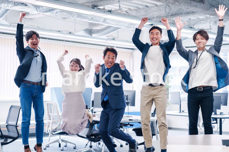 オフィスで大喜びをしてジャンプをするビジネスパーソン