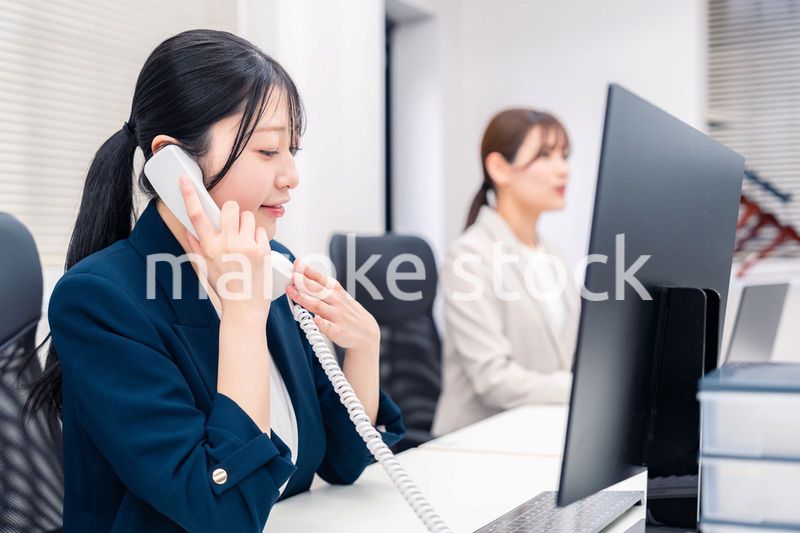 オフィスでにこやかに電話対応をするビジネスウーマン