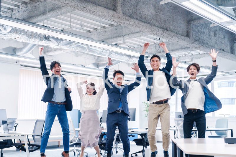 オフィスで大喜びをしてジャンプをするビジネスパーソン