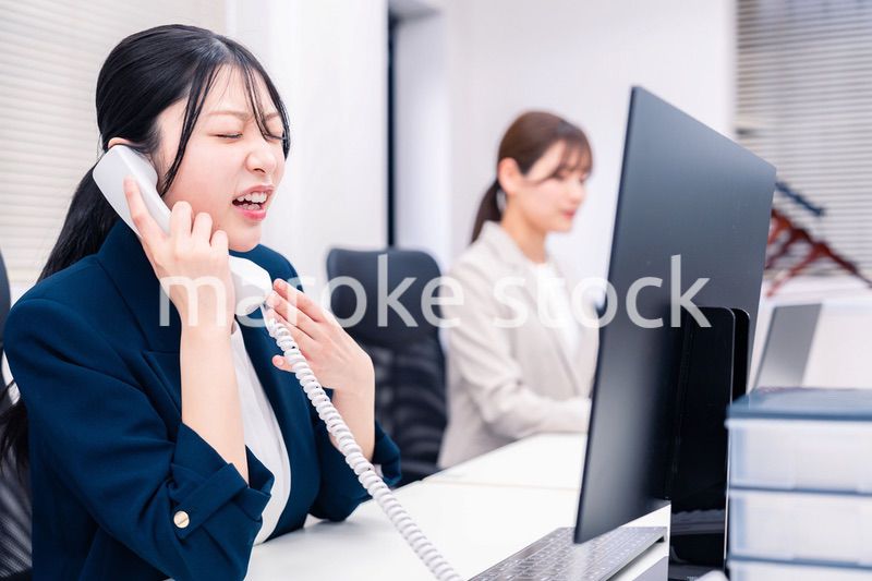 オフィスでお詫びの電話をする若いキャリアウーマン