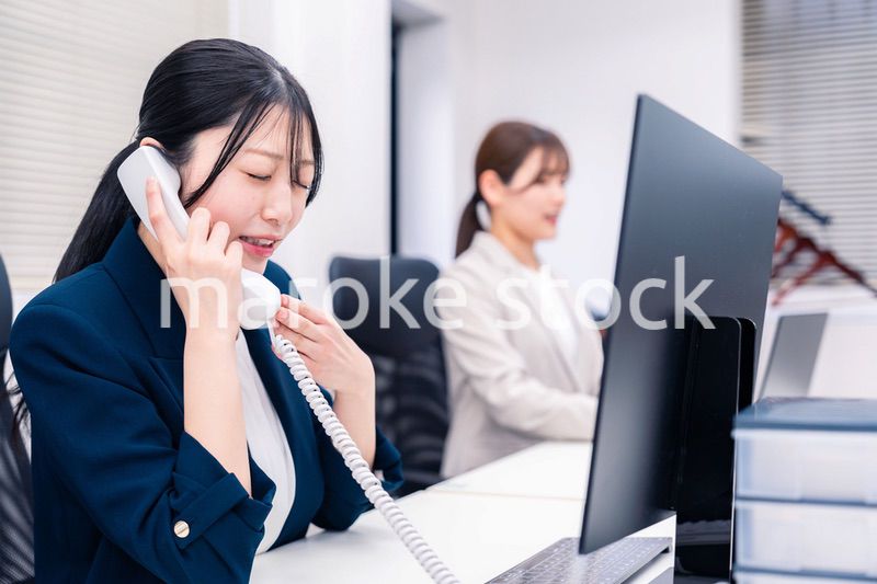 オフィスでお詫びの電話をする若いキャリアウーマン