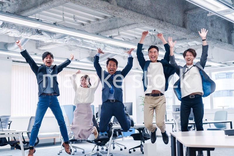 オフィスで大喜びをしてジャンプをするビジネスパーソン