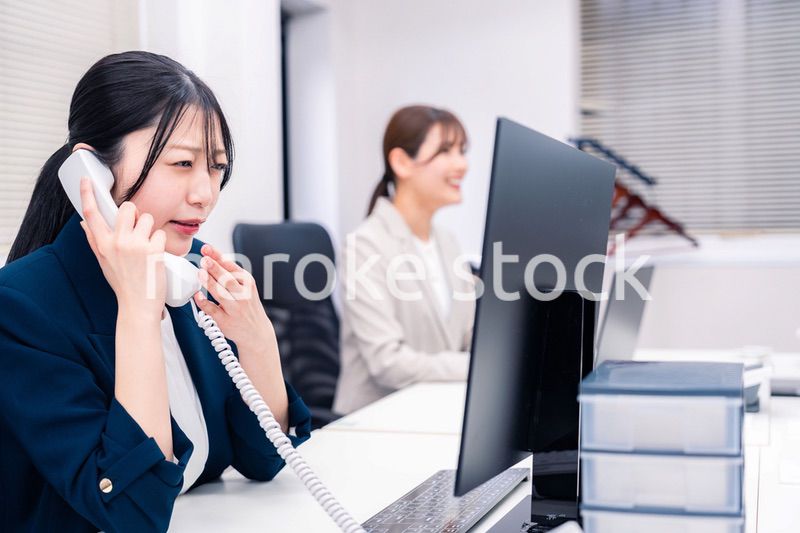 オフィスでお詫びの電話をする若いキャリアウーマン