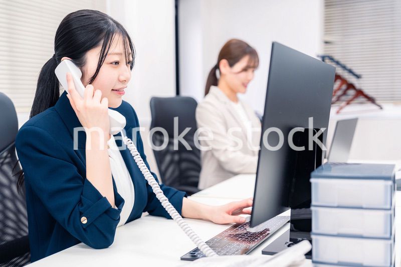 オフィスでにこやかに電話対応をするビジネスウーマン
