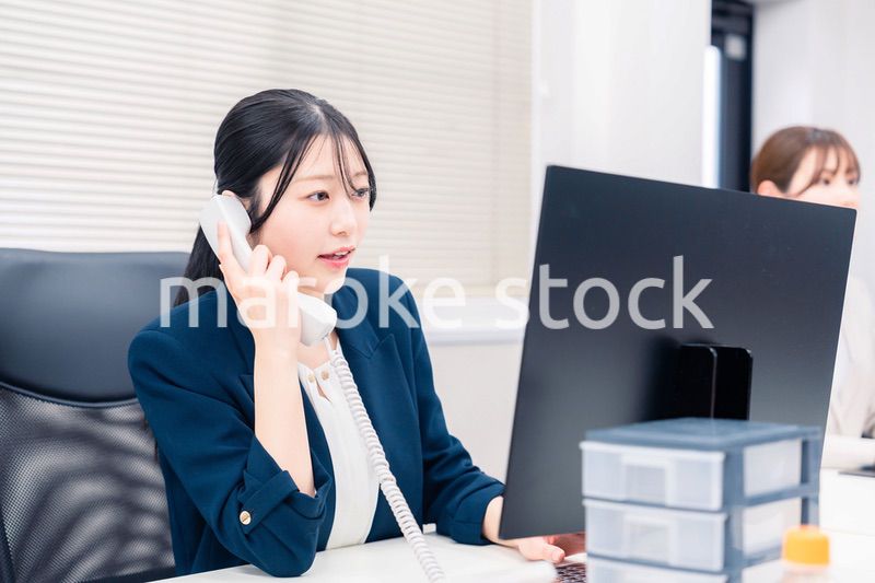 オフィスでにこやかに電話対応をするビジネスウーマン