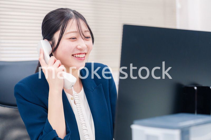 オフィスの固定電話で通話をする女性ビジネスパーソン