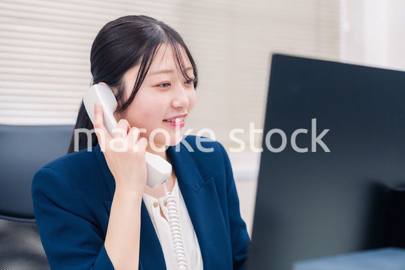 オフィスの固定電話で通話をする女性ビジネスパーソン