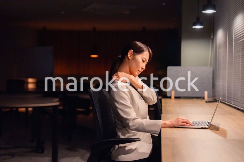 オフィスで暗くなるまで残業をして疲れる女性管理職