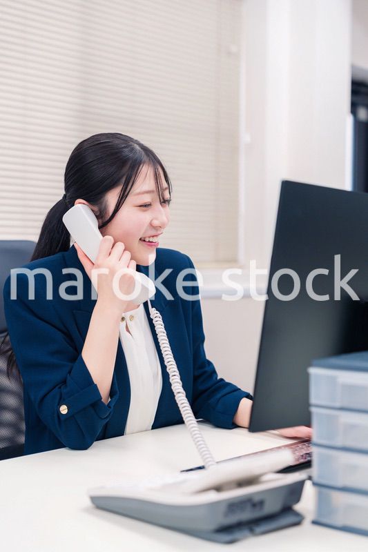 オフィスの固定電話で通話をする女性ビジネスパーソン