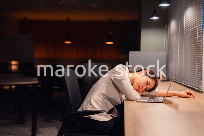 オフィスで暗くなるまで残業をして疲れる女性管理職