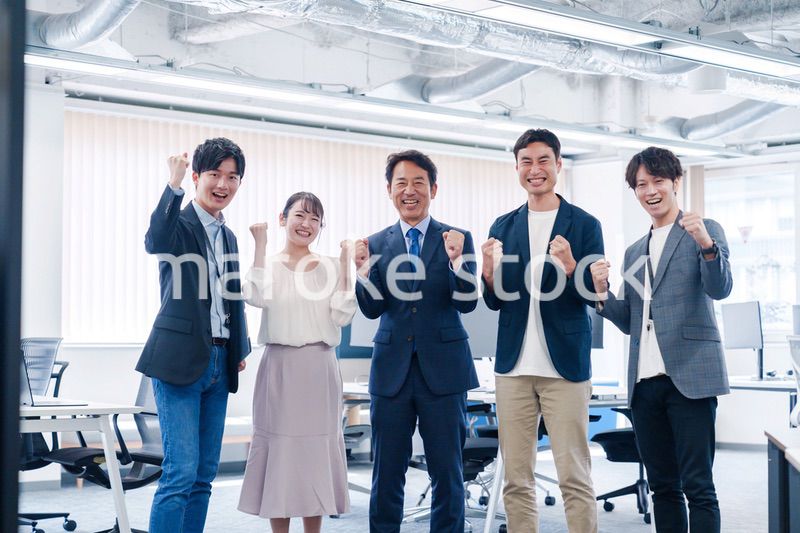 オフィスで笑顔でガッツポーズをするビジネスパーソン