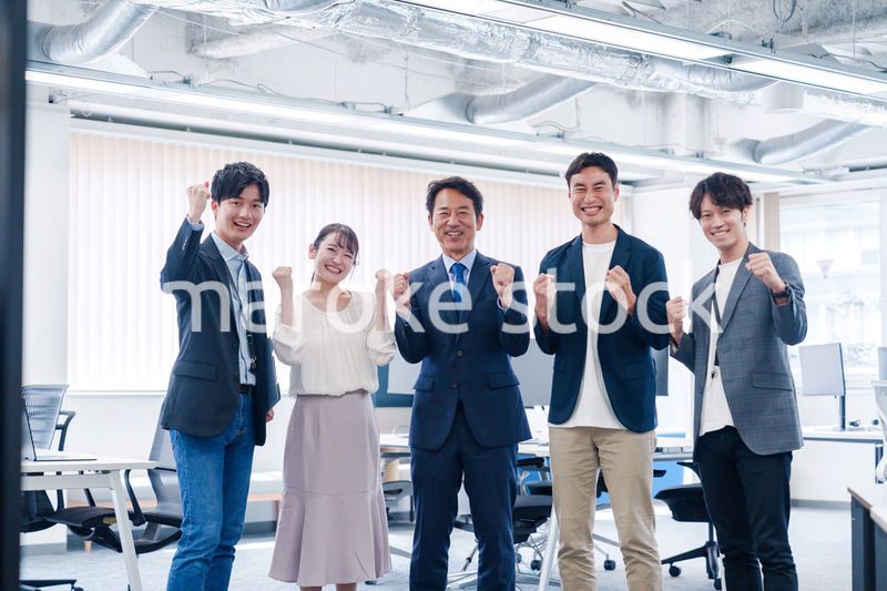 オフィスで笑顔でガッツポーズをするビジネスパーソン
