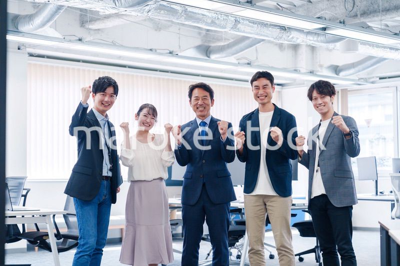 オフィスで笑顔でガッツポーズをするビジネスパーソン