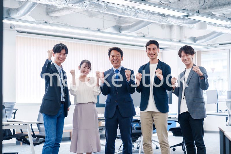 オフィスで笑顔でガッツポーズをするビジネスパーソン