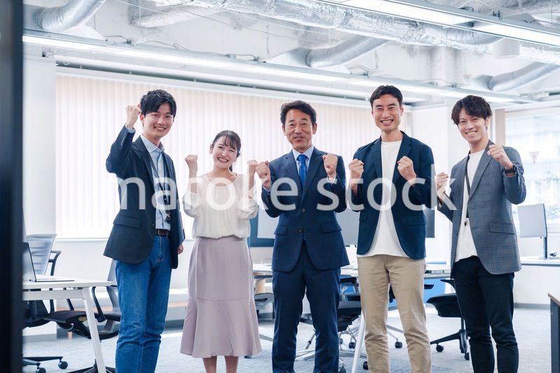 オフィスで笑顔でガッツポーズをするビジネスパーソン