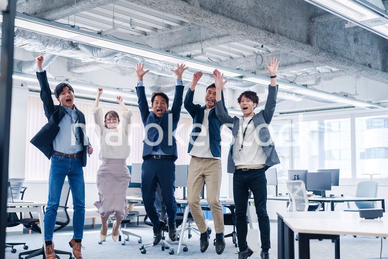 オフィスで大喜びをしてジャンプをするビジネスパーソン