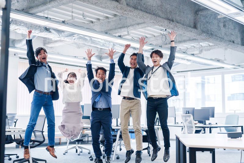 オフィスで大喜びをしてジャンプをするビジネスパーソン