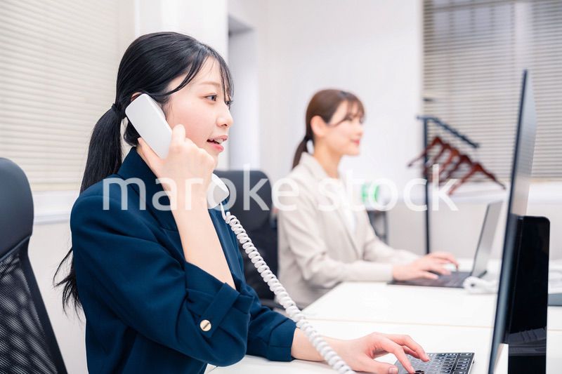 オフィスでにこやかに電話対応をするビジネスウーマン