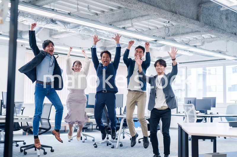 オフィスで大喜びをしてジャンプをするビジネスパーソン